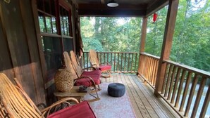 A covered porch with wooden railings, wicker chairs with red cushions, and a woven basket on a small table. - Brown County At It's Best Beautiful Cozy meticulous clean LG Game Room arcade! (Nashville)