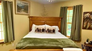 A bedroom with a wooden bed, green curtains, a ceiling fan, and a painting on the wall. - Brown County At It's Best Beautiful Cozy meticulous clean LG Game Room arcade! (Nashville)