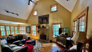 A spacious living room with a fireplace, a ceiling fan, and a television. - Brown County At It's Best Beautiful Cozy meticulous clean LG Game Room arcade! (Nashville)