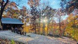 A rustic cabin with a metal roof, surrounded by a gravel path and autumn-colored trees. - Brown County At It's Best Beautiful Cozy meticulous clean LG Game Room arcade! (Nashville)