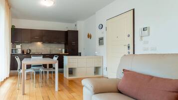 Eine moderne Wohnung mit Essbereich, Küchenzeile und Wohnzimmer mit Sofa.