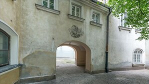 Holvikaarinen oviaukko, joka johtaa sisäpihalle, jonka lattia on päällystetty mukulakivillä.