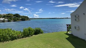 A coastal view with a clear sky, a grassy area, and a white building with air conditioning units. - Magnificent seaside studio (Gosier)
