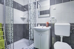 A modern bathroom with a glass shower enclosure, a white sink, and a toilet. - Studio with city view (Pula)