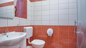 Une salle de bain avec un lavabo blanc, des toilettes et un sèche-mains fixé au mur.