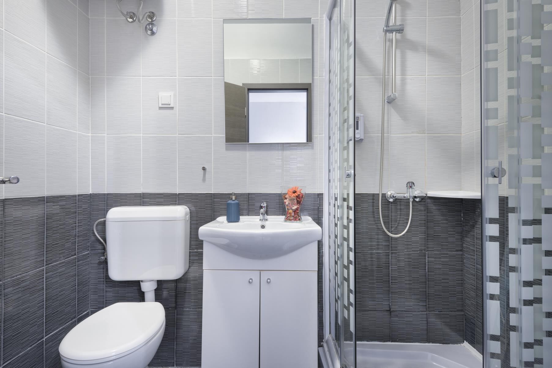 A modern bathroom with a toilet, sink, and shower.