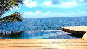 Una terraza de madera con vista despejada al océano y una piscina.