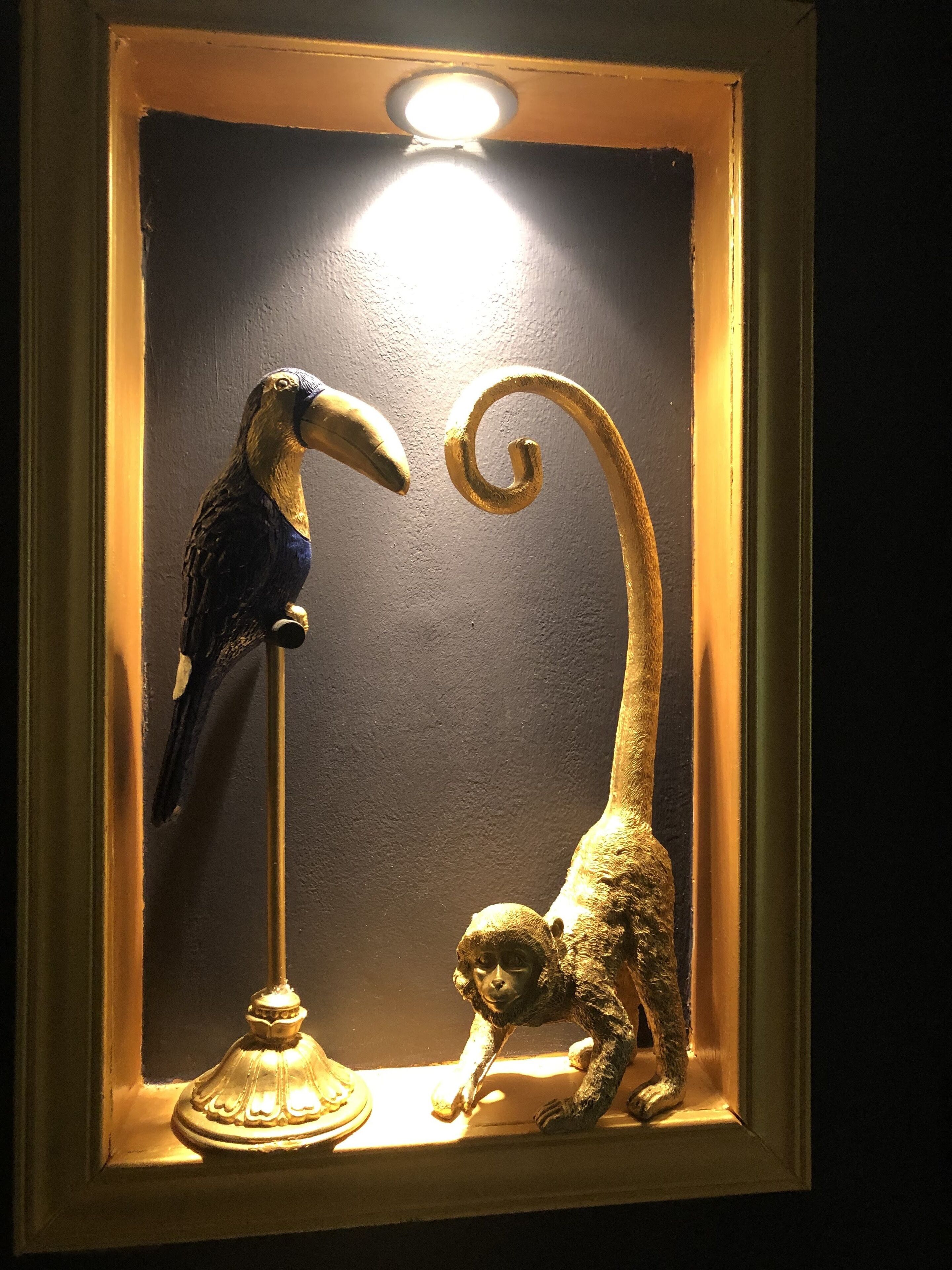 Una escultura enmarcada que muestra un pájaro y un mono.