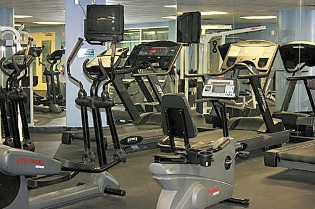 Une salle de sport équipée de divers appareils d’exercice, notamment des tapis de course et des appareils de musculation elliptique.