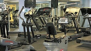 Ein Fitnessstudio mit verschiedenen Trainingsgeräten, darunter Laufbänder und Crosstrainer.