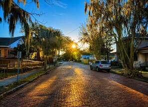A cobblestone street lined with trees and houses, with a car parked on the side. - Historic Victorian Restoration (Savannah)