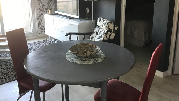 Ein Essbereich mit einem runden Tisch, zwei Stühlen, einem Fernseher und einer Lampe.