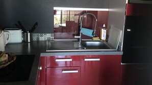 Eine moderne Küche mit roten Schränken, einer Edelstahl-Spüle und einem eingebauten Backofen.