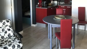 Eine moderne Küche mit roten Schränken und einem Essbereich mit rundem Tisch und roten Stühlen.