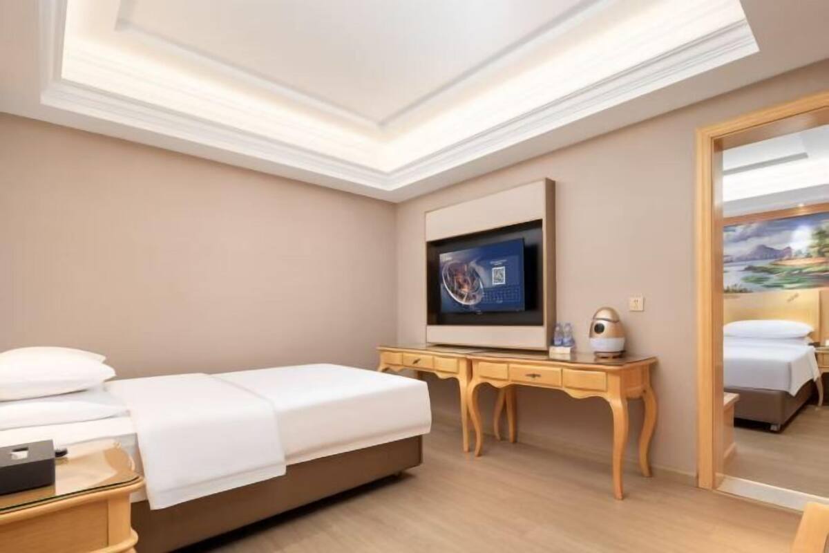 A hotel room with a bed, a desk, a television, and a mirror.