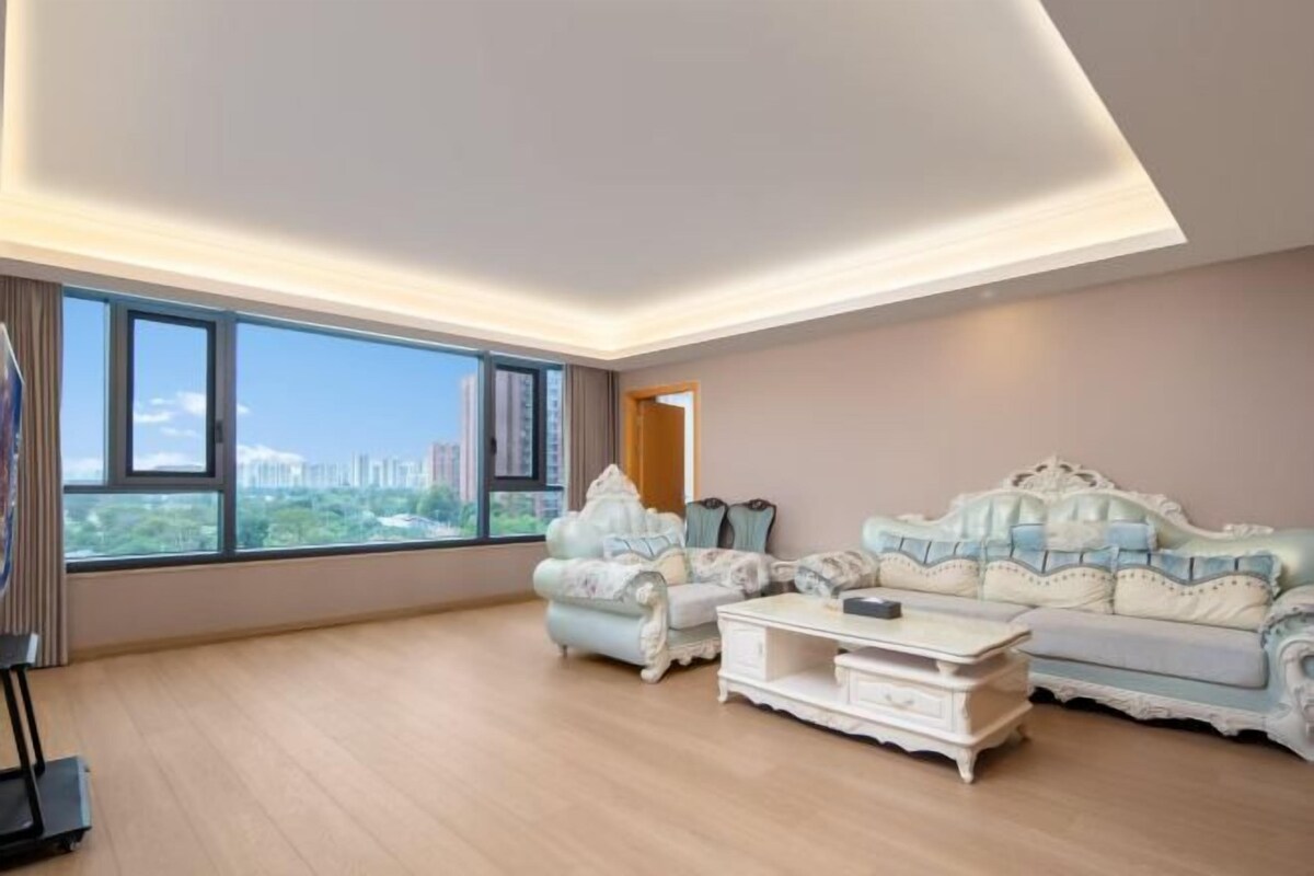 A spacious living room with a large window, a sofa set, and a coffee table.