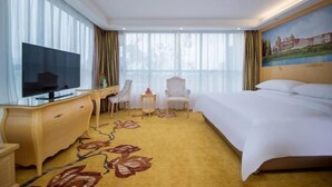 A hotel room with a large bed, a TV, a desk with a chair, and a small table. - Vienna Hotel (Wuhan Nanhu Huazhong Agricultural University) (Wuhan)