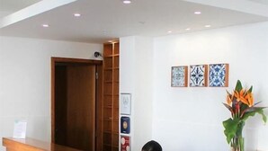 A reception desk with a wooden finish, a glass partition, and a framed certificate on the wall. - Arcangel Hotel (Lagoa)