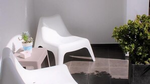 A patio area with two white plastic chairs, a small table, and two potted plants. - Arcangel Hotel (Lagoa)