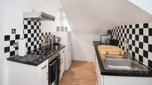 A compact kitchen with black and white checkered backsplash, a stainless steel sink, and a modern stove.