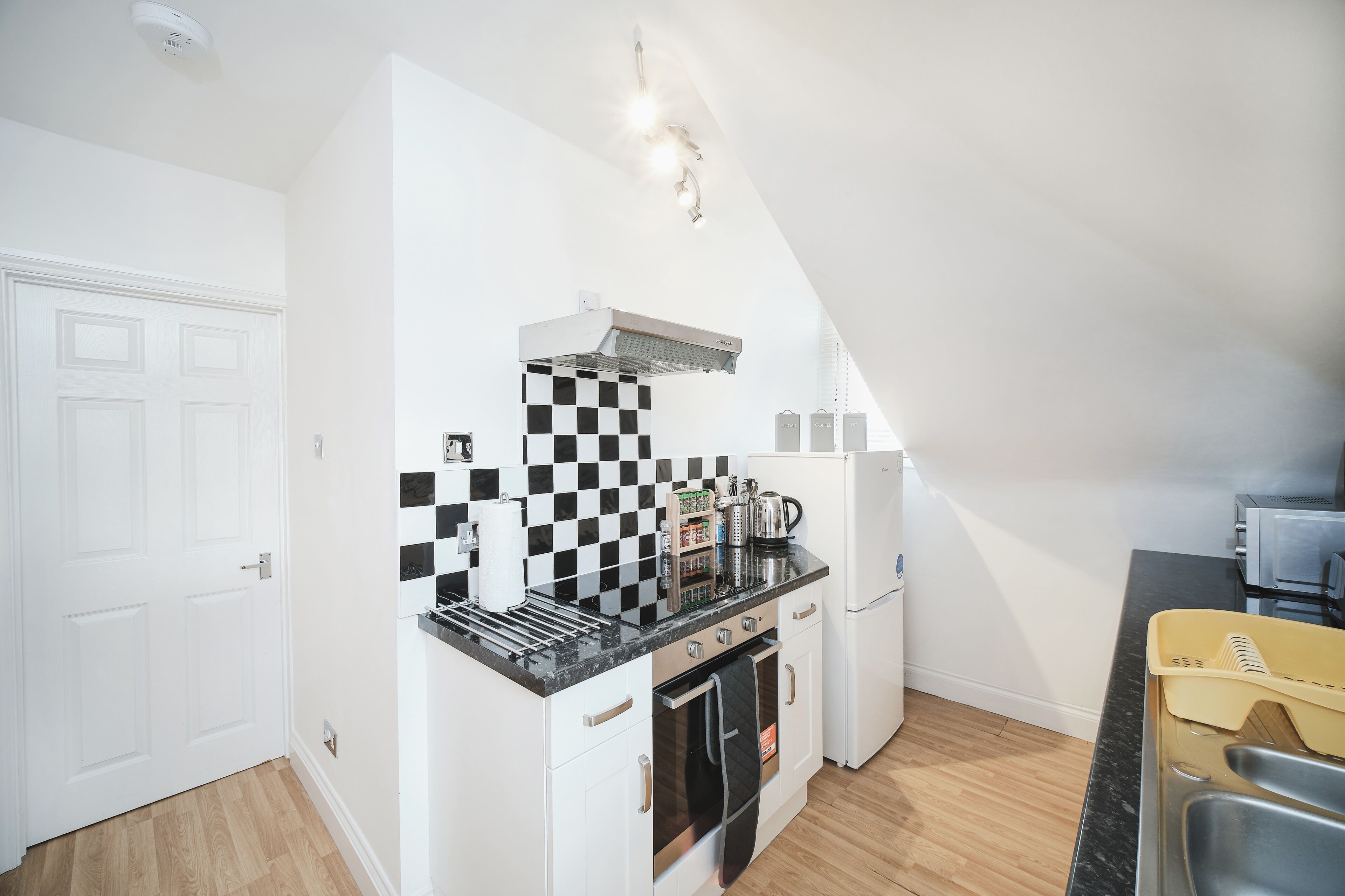 Une cuisine de taille réduite avec un crédence à carreaux noirs et blancs, une cuisinière, un four et un réfrigérateur.