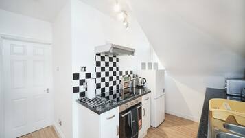 Une cuisine de taille réduite avec un crédence à carreaux noirs et blancs, une cuisinière, un four et un réfrigérateur.