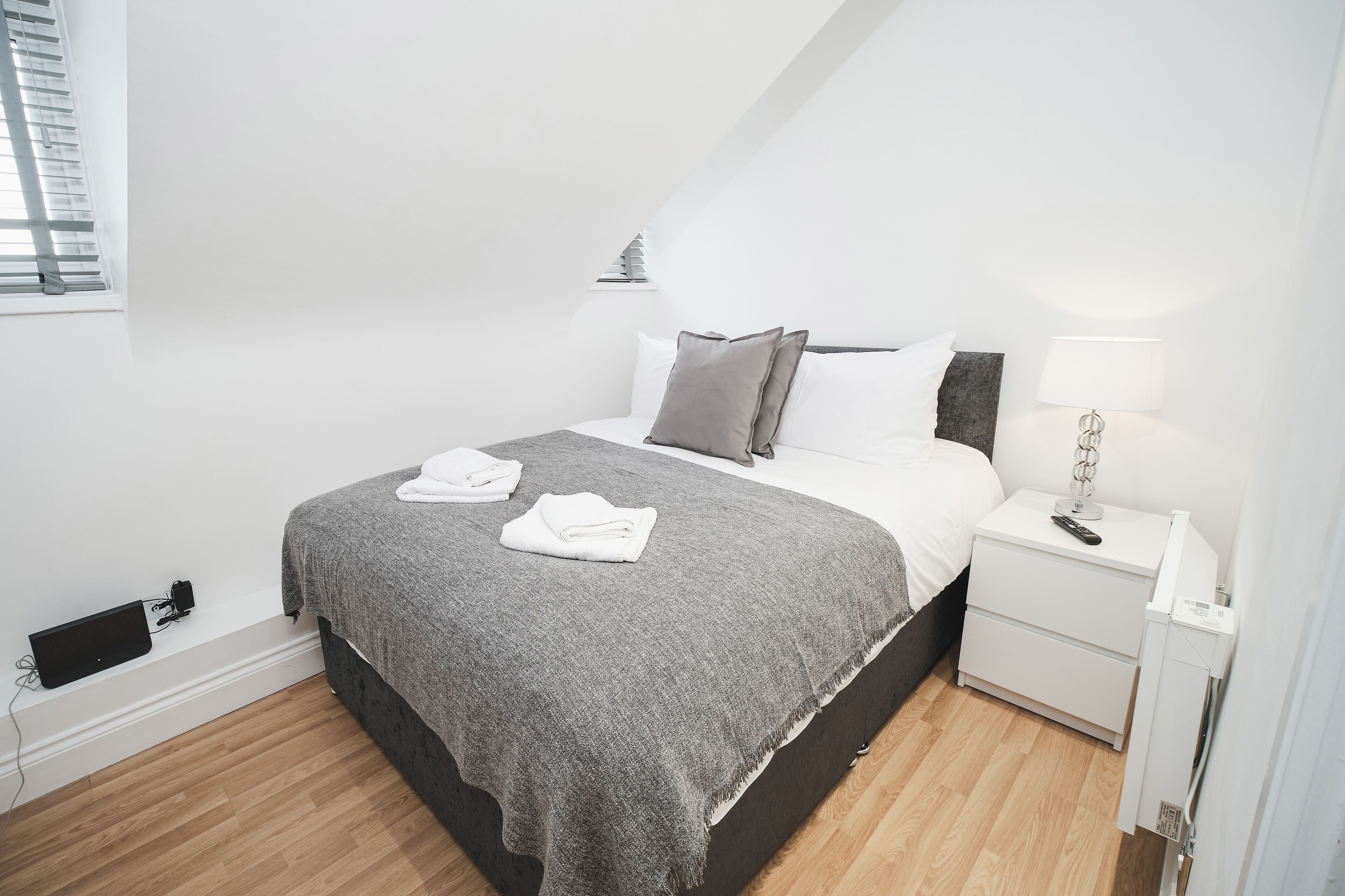 A modern bedroom with a bed, bedside table, and a small bedside lamp.