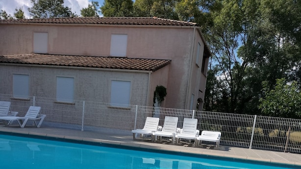 En swimmingpool med liggestole og fliseterrasse.