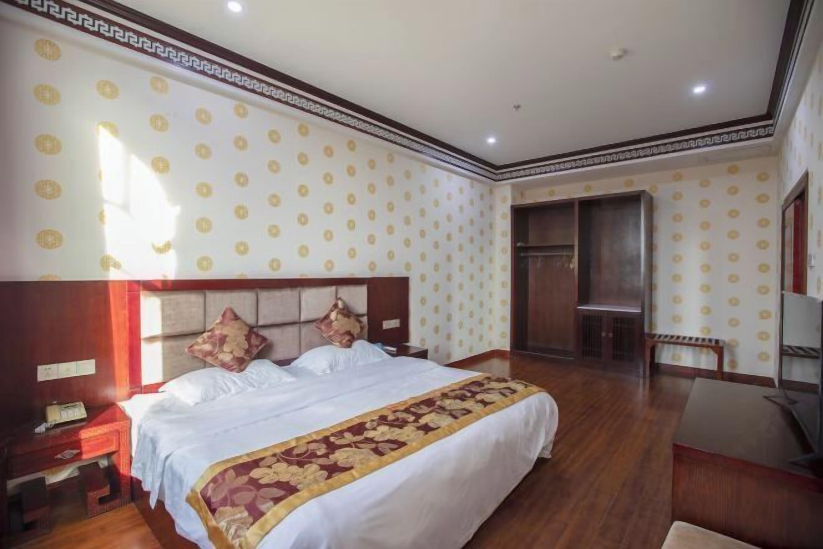 Een hotelkamer met een groot bed, houten vloeren, een bureau en een televisie.
