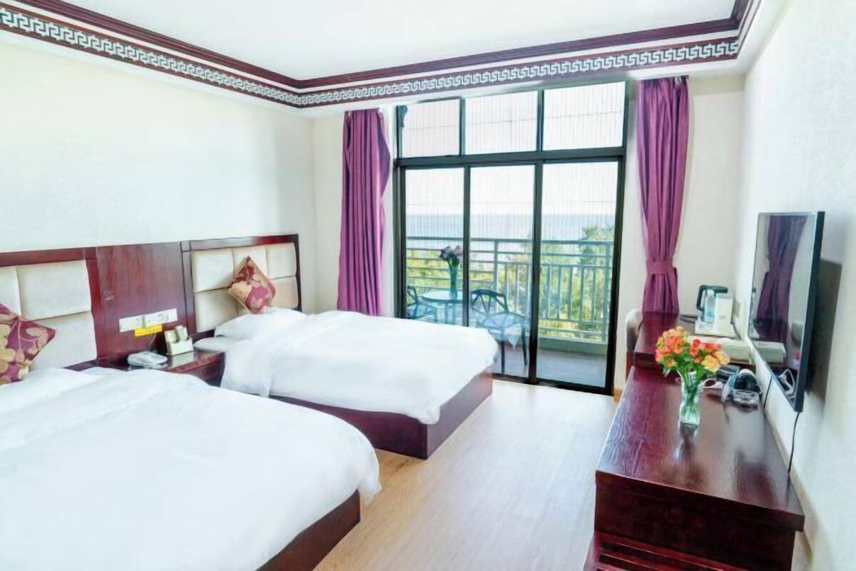 Une chambre d’hôtel avec deux lits, une commode en bois, une télévision et un balcon avec vue.