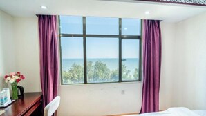 Une chambre d’hôtel avec une grande fenêtre, un lit, un bureau et une chaise.