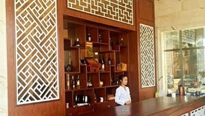 Un espace d’accueil avec un comptoir en bois et des étagères remplies de bouteilles et d’objets décoratifs.