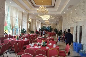 A spacious banquet hall with round tables, red chairs, and chandeliers. - Dongxing Zijin Hotel (Dongxing)