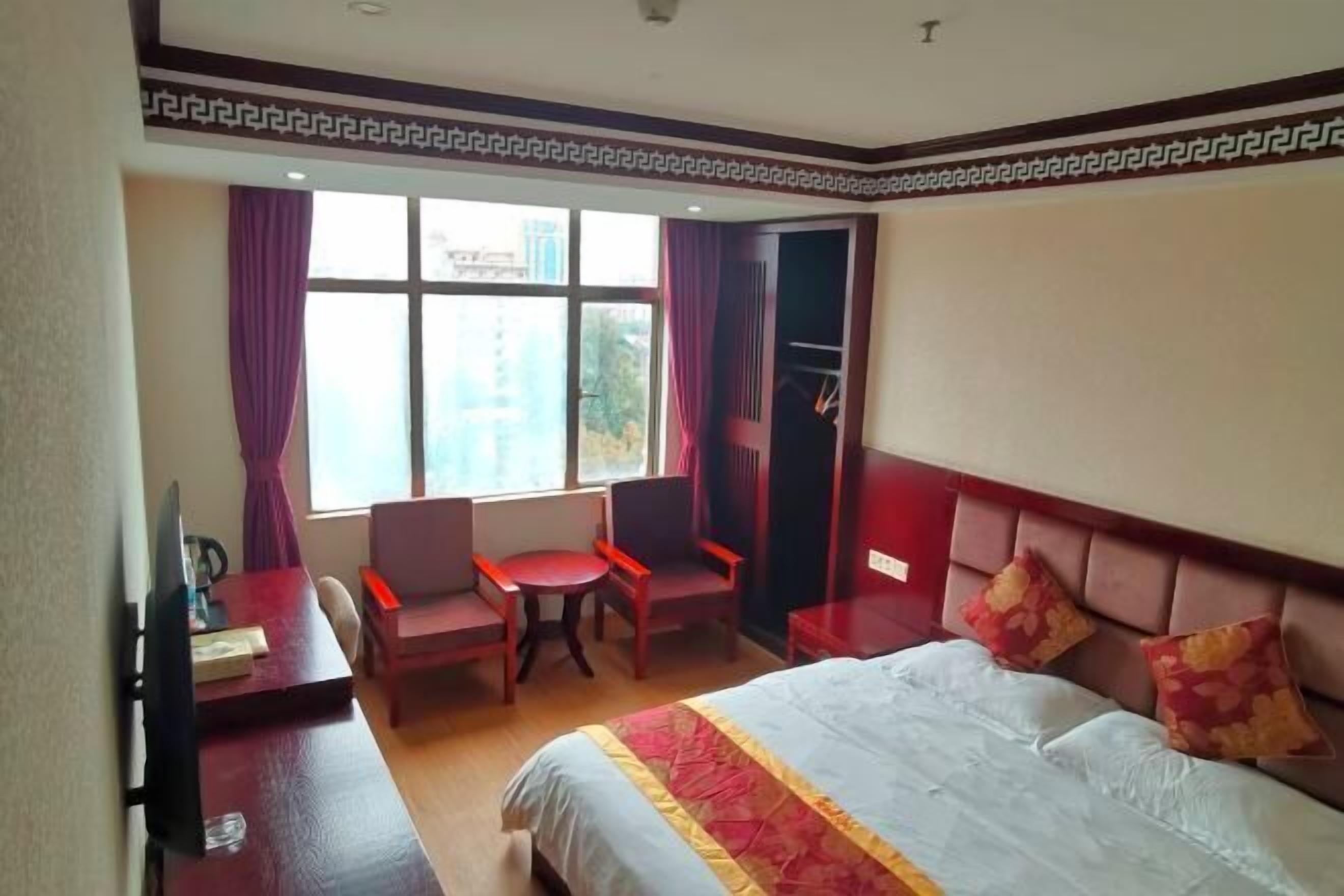 A hotel room with a bed, a desk, a chair, and a window with curtains.