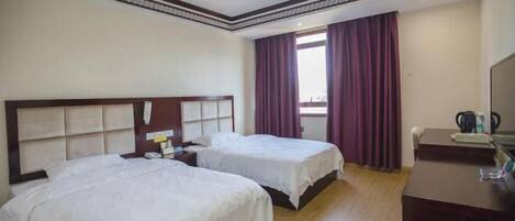 Habitación de hotel con dos camas, un escritorio y una ventana con cortinas.