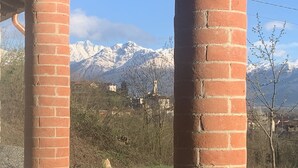 A brick structure with a view of snow-capped mountains and a distant village. - Remarkable 6 Bedrooms Villapiemonte With Land (Cerrione)