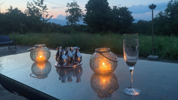 A table with decorative glassware and a glass of water, set outdoors with a view of trees and a lamp post in the background. - Remarkable 6 Bedrooms Villapiemonte With Land (Cerrione)