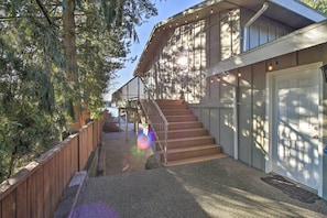 A building with a wooden exterior, a staircase leading to a second floor, and a door with a doormat.