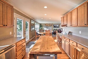 A spacious kitchen with wooden cabinets, a granite countertop, and a large dining table.