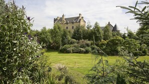 A large, historic building with a well-maintained garden and a grassy lawn in the foreground. - The Manor at Plane Castle - Sleeps 8 - Pets Ok (Falkirk)
