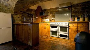 A rustic kitchen with stone walls, wooden cabinets, a stove, and a microwave. - The Manor at Plane Castle - Sleeps 8 - Pets Ok (Falkirk)