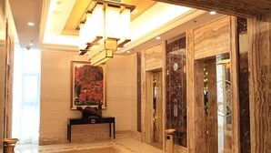 A lobby with a marble floor, a large painting, and two elevators. - Shenglin International Hotel (Gaobeidian)