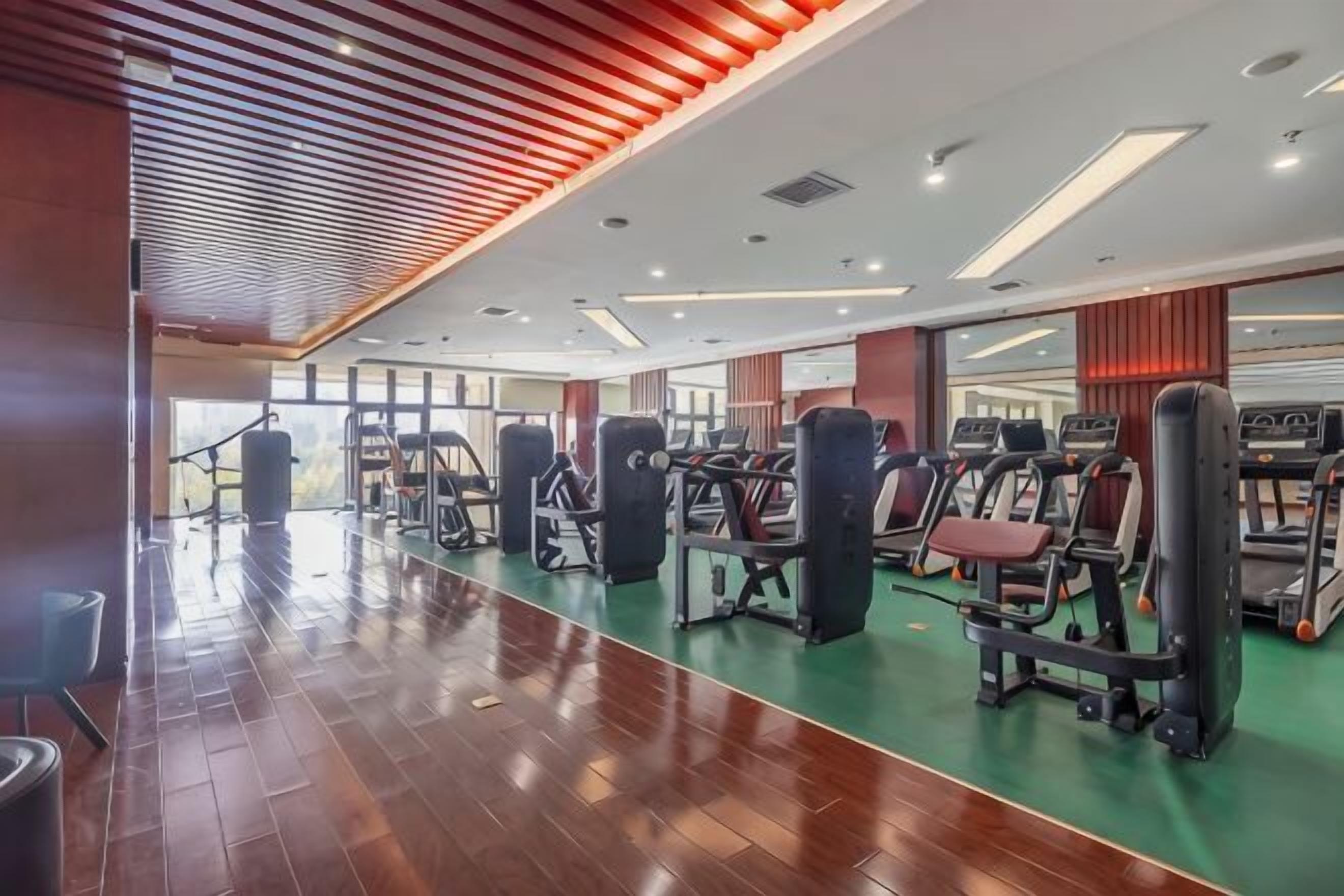 Una palestra con attrezzature per esercizi, pavimento in legno e un'ampia finestra.