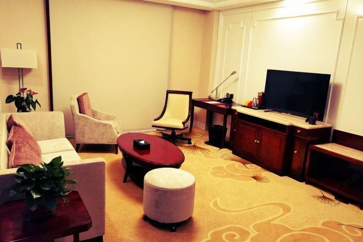 A living room with a sofa, armchairs, a coffee table, a television, and a cabinet.
