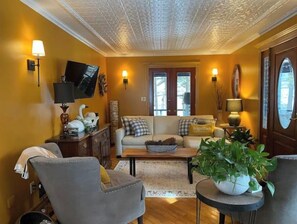 Relax in this inviting living room with a sofa set, coffee table, and side table, featuring a television and a large window with a view of the outdoors.