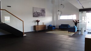 Un interno moderno con una scala, un armadio in legno, divani blu, un'ampia finestra e un'opera d'arte appesa al muro.