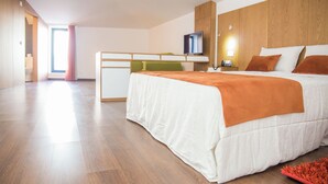 Una camera d'albergo moderna con un letto, una scrivania, una televisione e vista all'esterno.