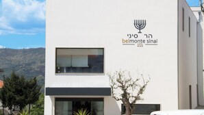 A modern building with a sign for 'Belmonte Sinai Hotel' featuring a menorah symbol. - Belmonte Sinai Hotel (Belmonte)