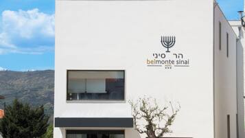 A modern building with a sign for 'Belmonte Sinai Hotel' featuring a menorah symbol.