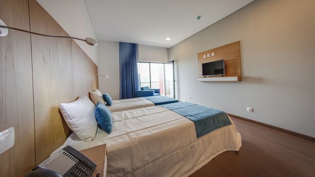 A modern hotel room with two beds, a desk with a computer, a TV mounted on the wall, and a large window with curtains. - Belmonte Sinai Hotel (Belmonte)